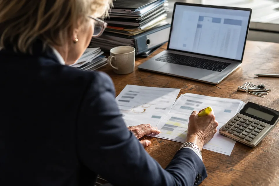 Finance director marking up a printed accounts payable software quote beside a laptop and calculator